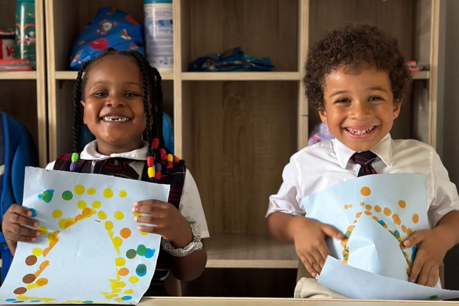 Two students holding up artwork they made in class.