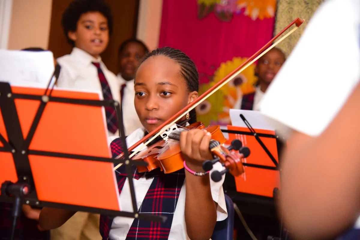 A student playing violin at a school recital.