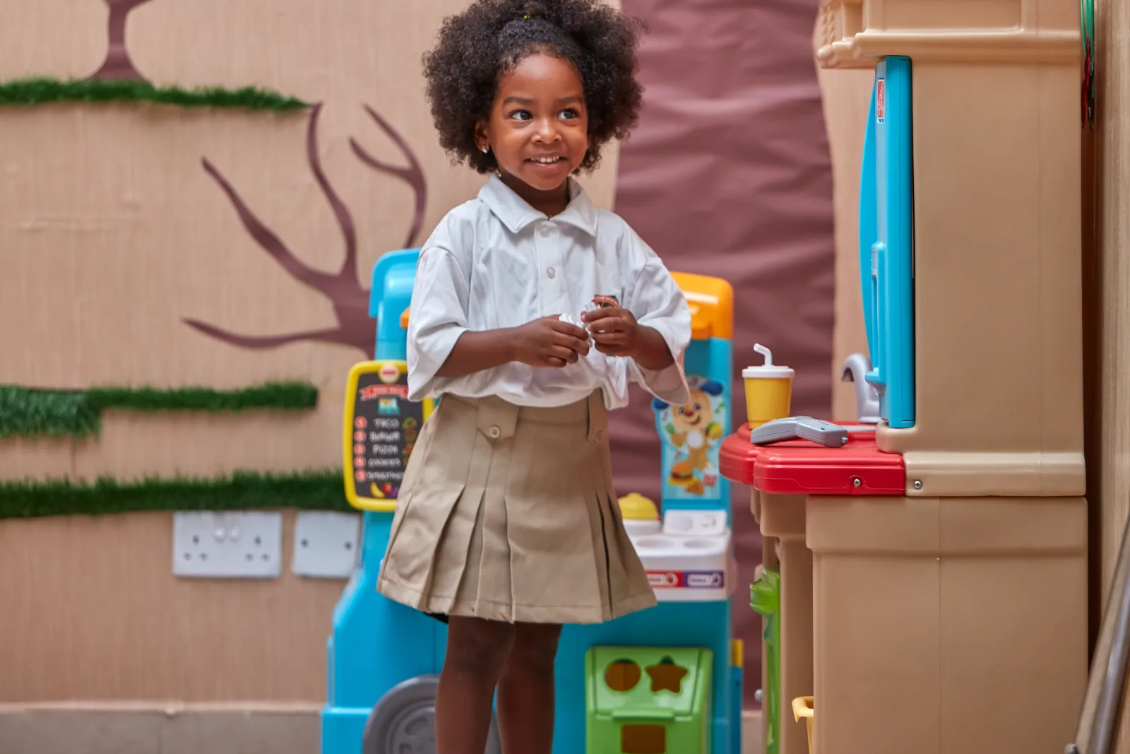 A student playing at a classroom play-kitchen.